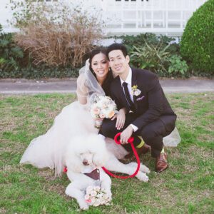 Bride and groom with dog in garden.