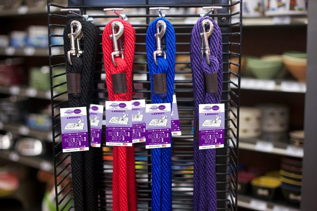 Colored dog leashes displayed on store rack.